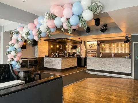 Pastel pink and blue balloon arch with eucalyptus over the dance-floor entry at Hidden Burnley.