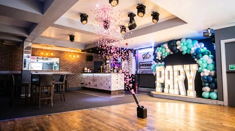 Gender-reveal pink confetti cannon mid-burst at Hidden Burnley.