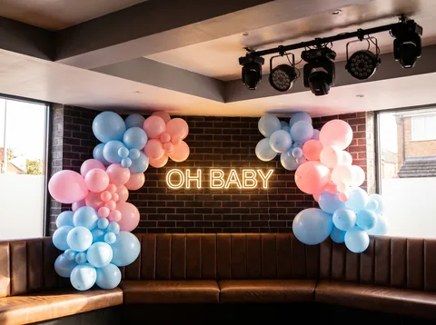 Photo corner at Hidden Burnley with pastel balloon clusters framing a warm-white 'OH BABY' neon-style sign.