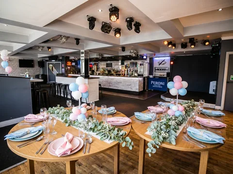 Round tables laid for a baby shower lunch at Hidden Burnley with pastel place settings.