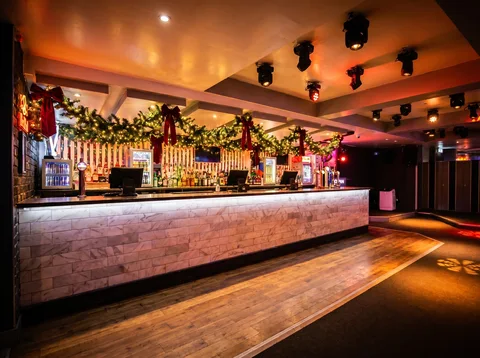 Bar at Hidden Burnley dressed in green pine garland with red velvet ribbon and warm fairy lights.