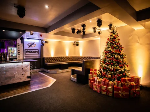 Tall decorated Christmas tree in red and gold next to the booth wall at Hidden Burnley.